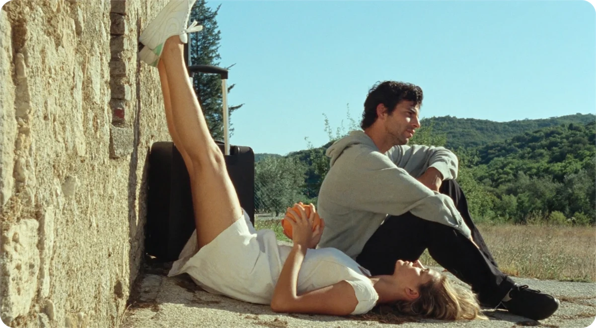 Two people resting against a stone wall in summer sun